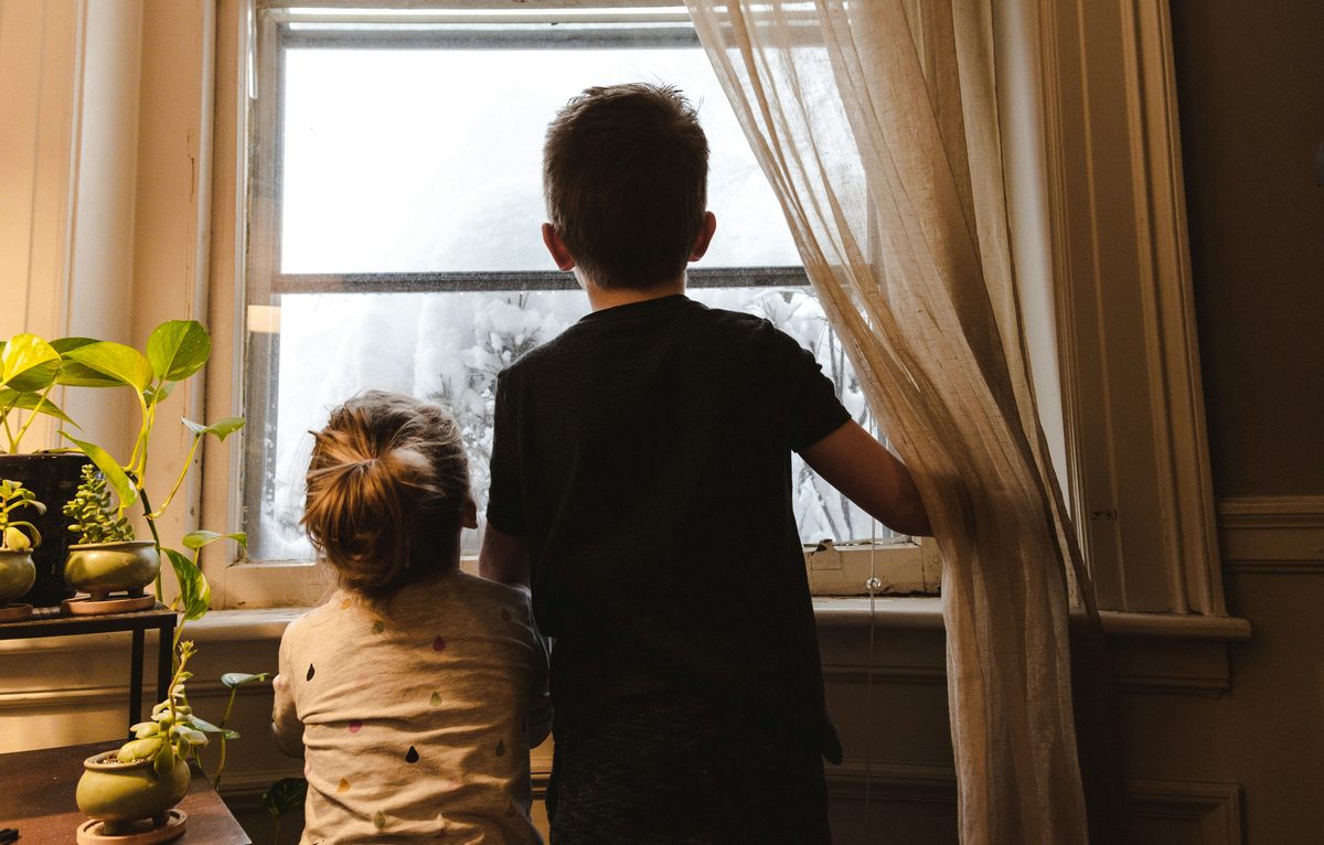 Due bambini che guardano fuori dalla finestra